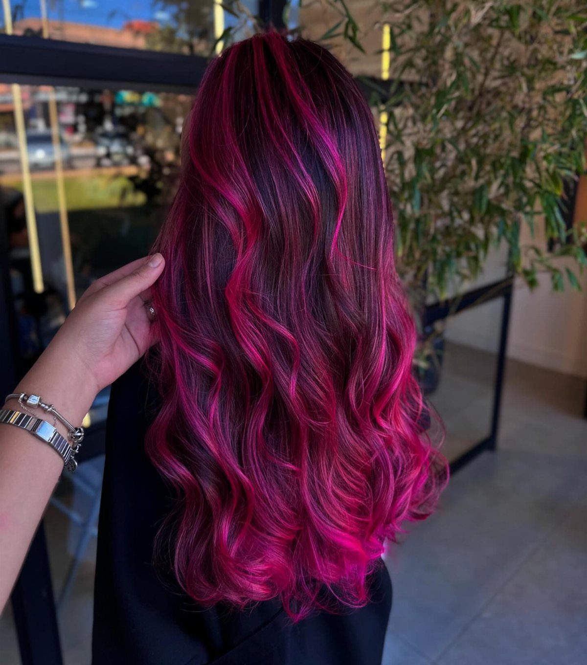 Long curled dark hair with vivid magenta streaks and pink ends