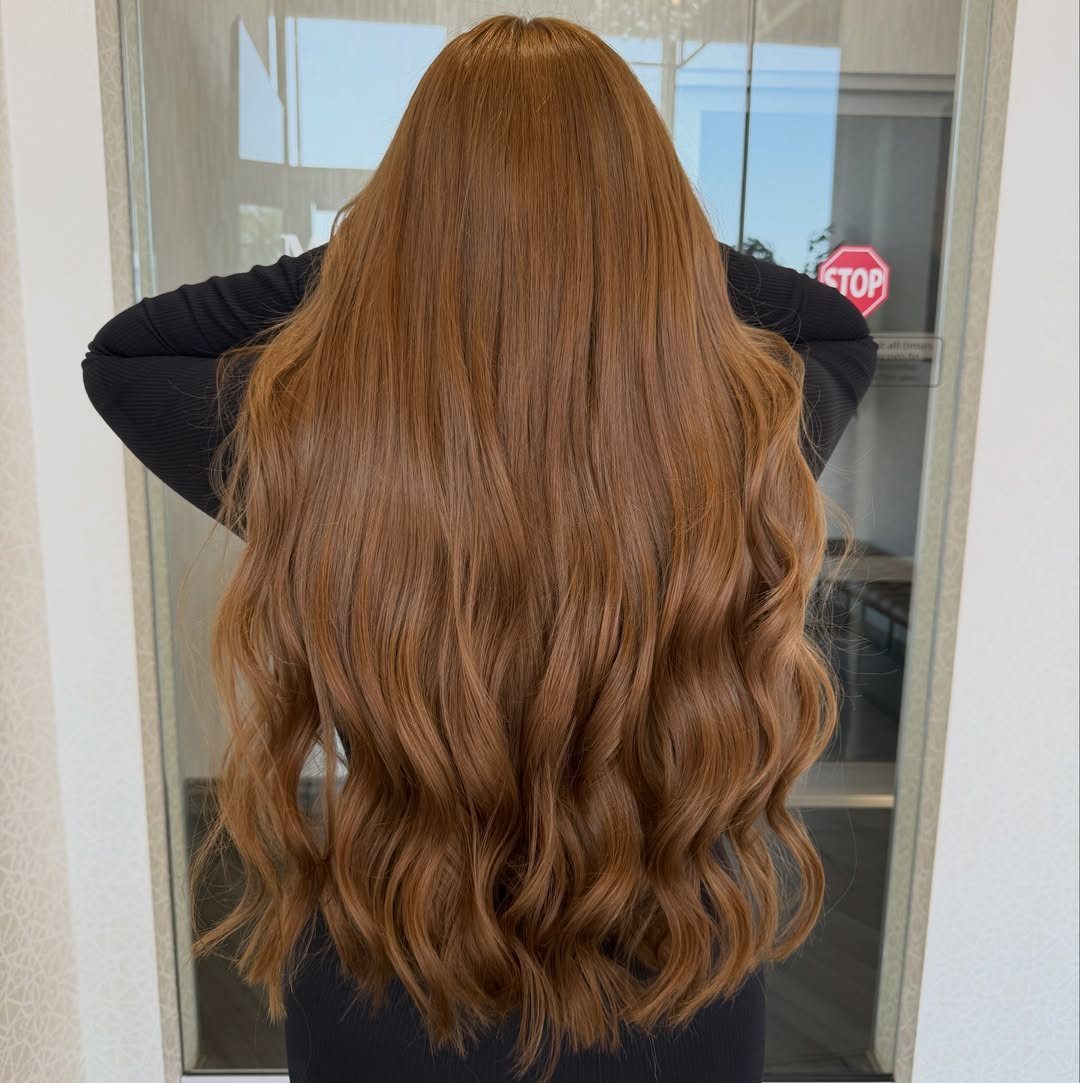 Long wavy auburn hair shows fine golden highlights from the back