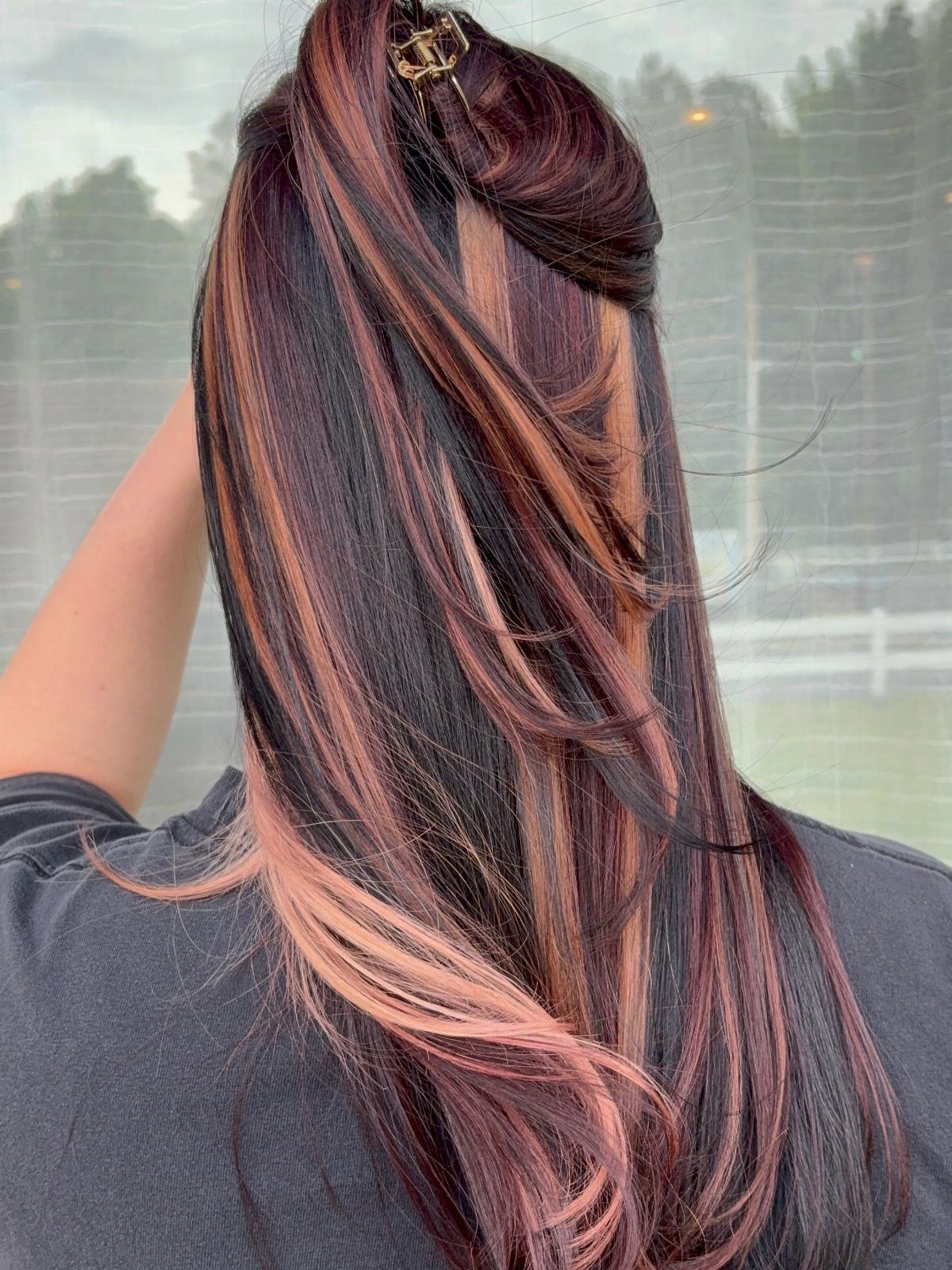 Long auburn hair shows copper highlights and lighter streaks through its layers