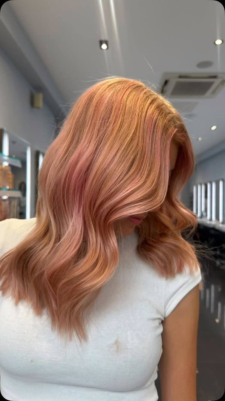Wavy bright copper hair with rose-gold accent pieces in a salon
