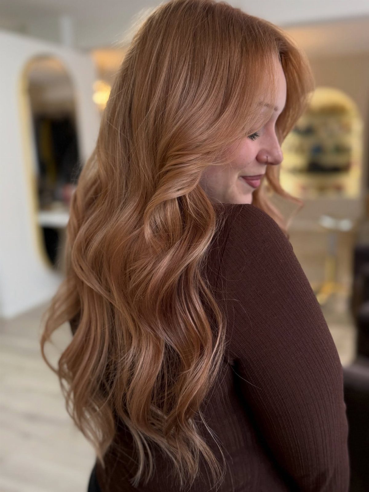 Long wavy copper hair with lighter honey-toned balayage in a salon