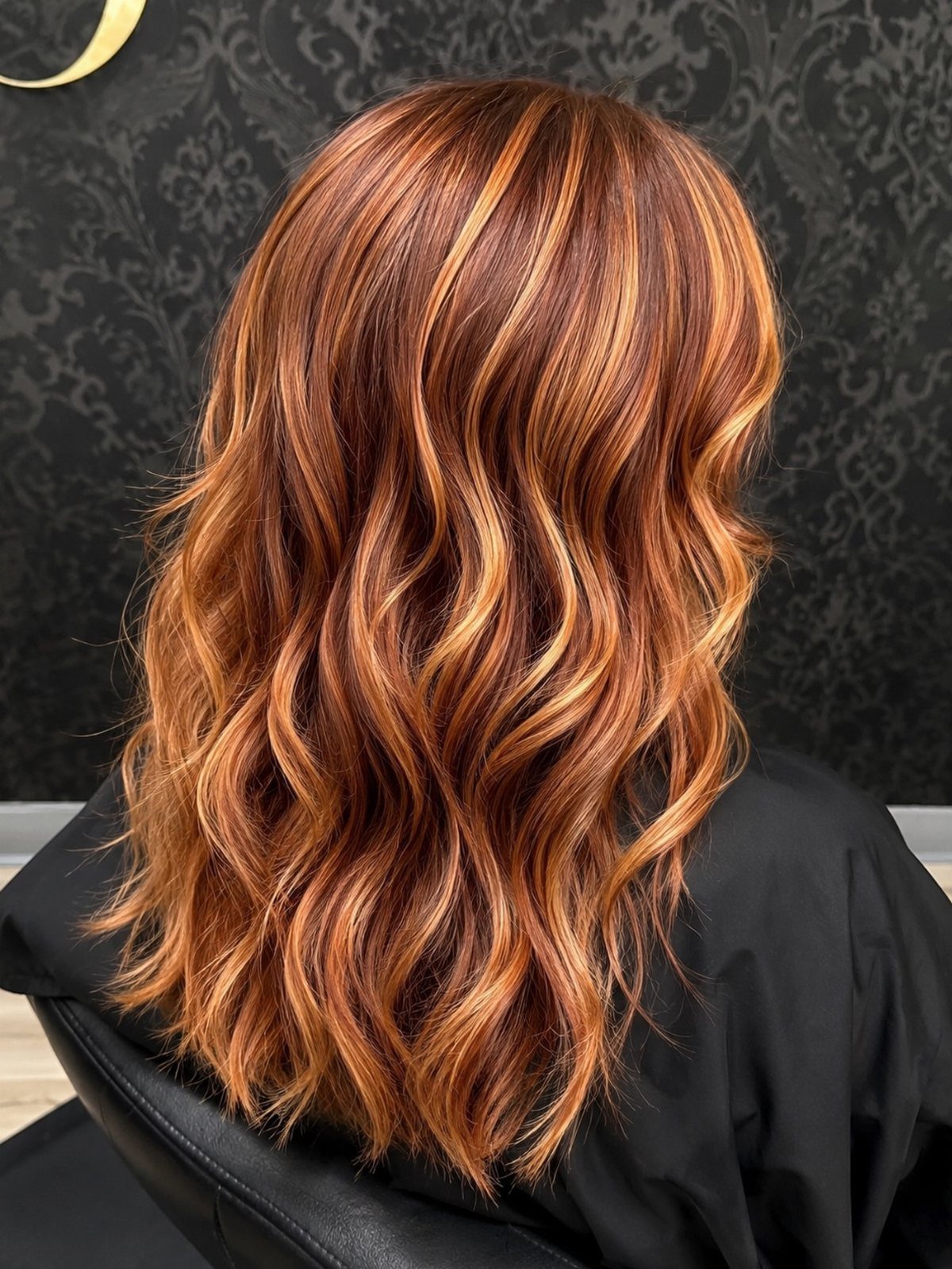Wavy auburn hair with vivid copper and caramel highlights in a salon