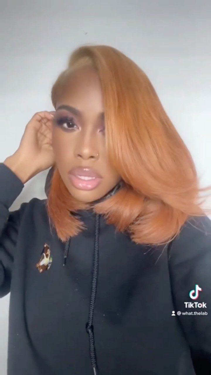 Person with smooth coppery reddish-blonde hair swept over one shoulder