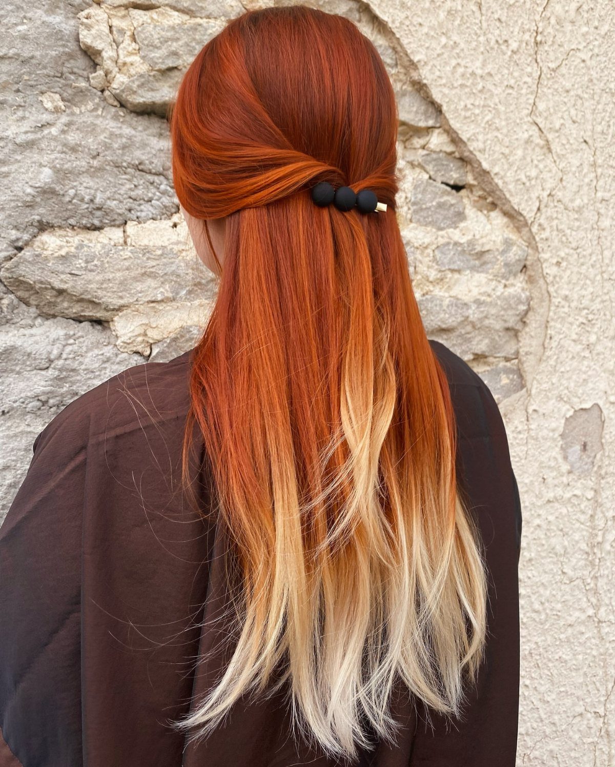 Ginger-red hair fading into long blonde ends, secured with a black clip