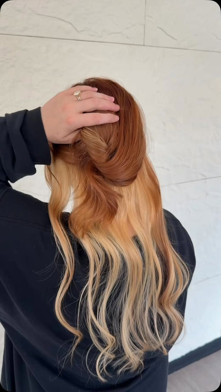 Long wavy copper-red hair with contrasting toffee-blonde sections styled in a twist