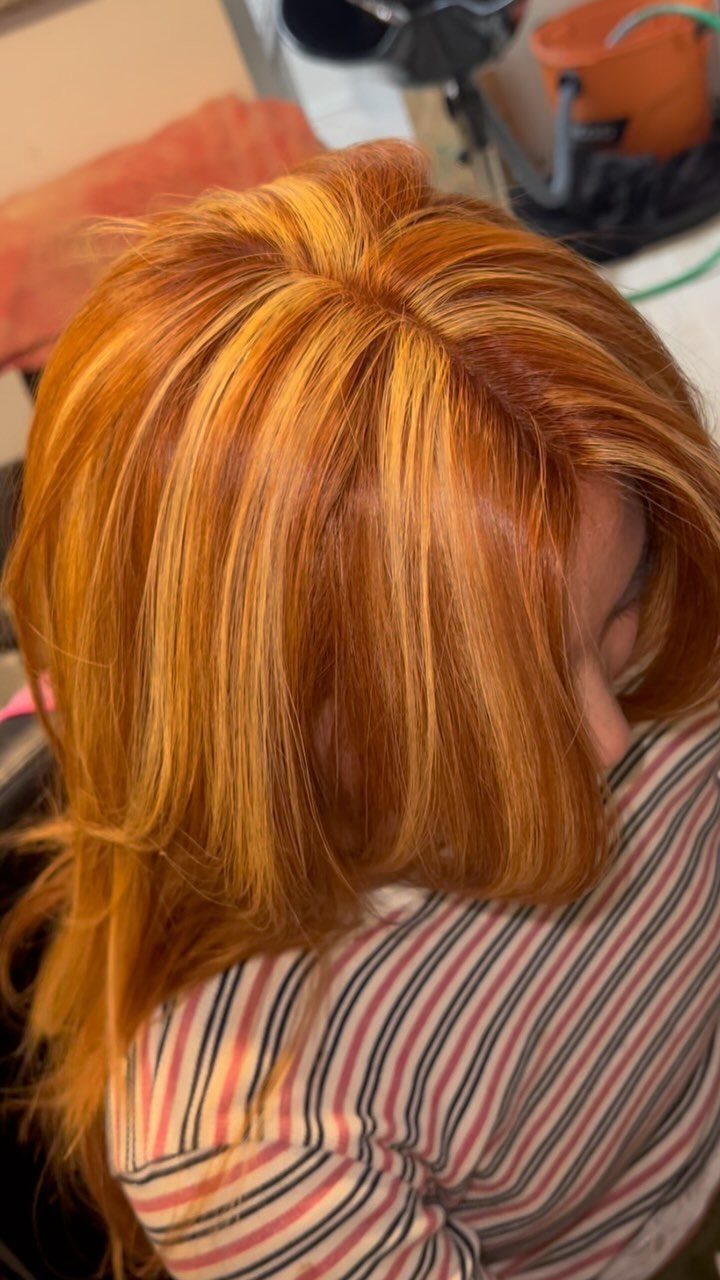 Copper hair with golden blonde highlights shown from above in a salon