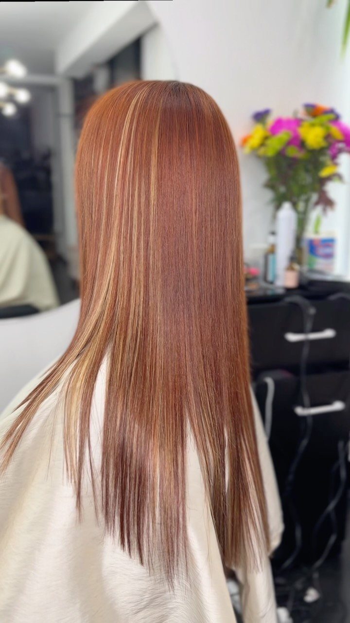 Long reddish-blonde hair with lighter blonde strands in a salon