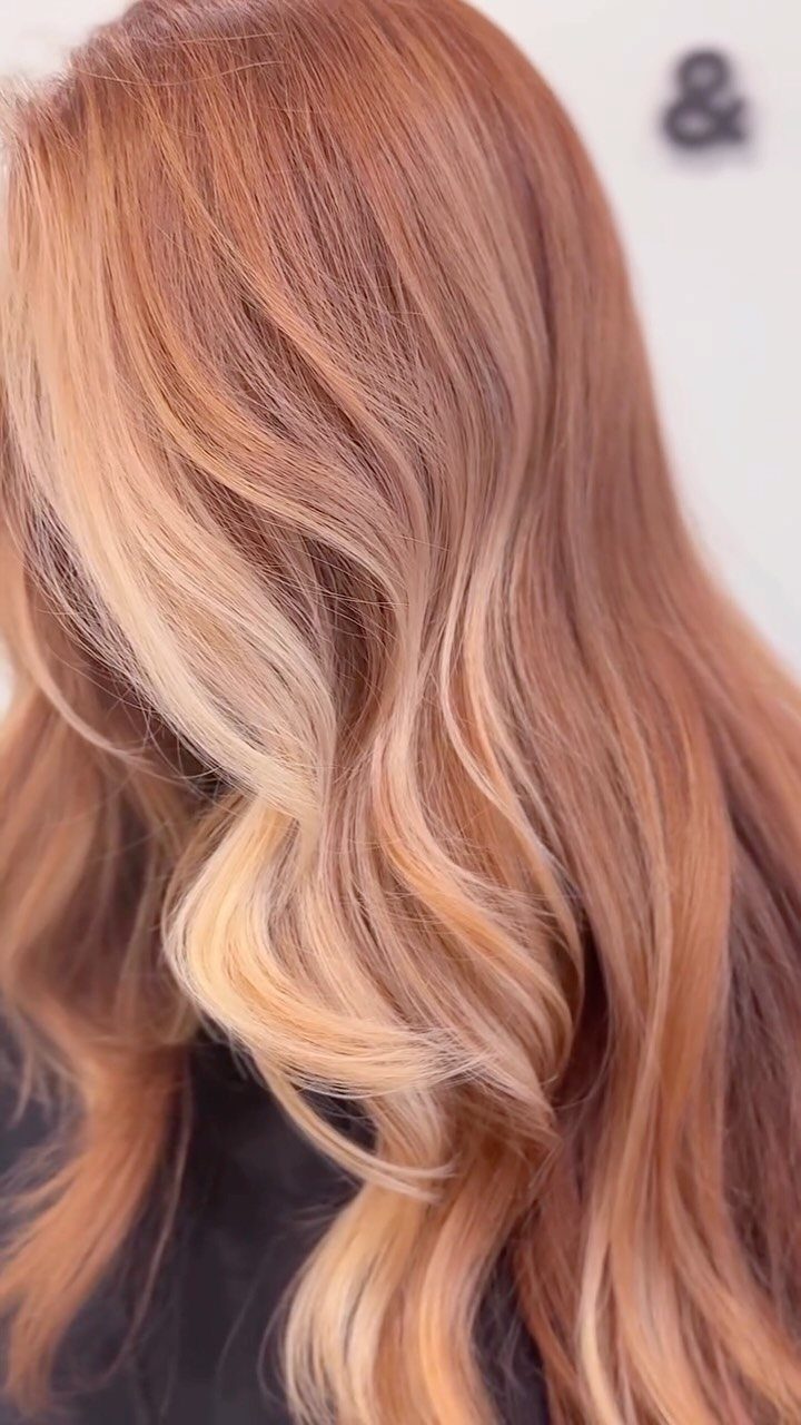 Strawberry blonde balayage with flowing golden highlights and soft curls