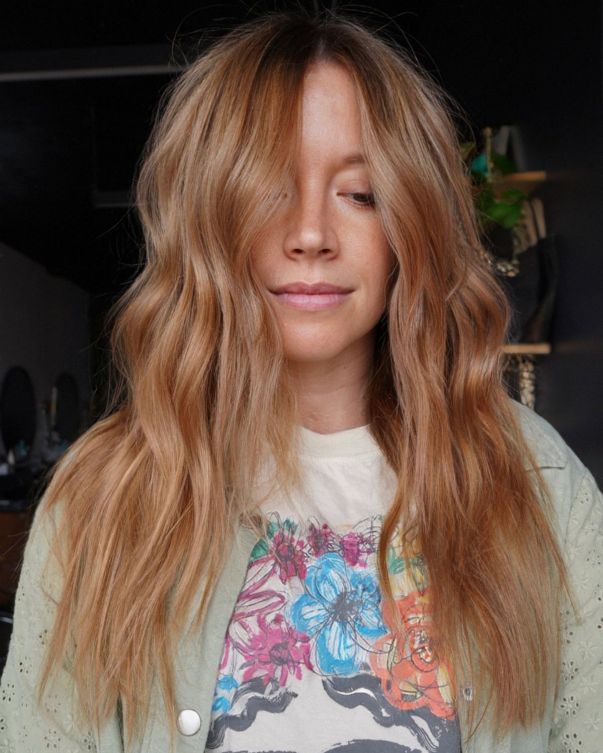 Woman with long wavy strawberry hair and lighter blonde balayage framing her face