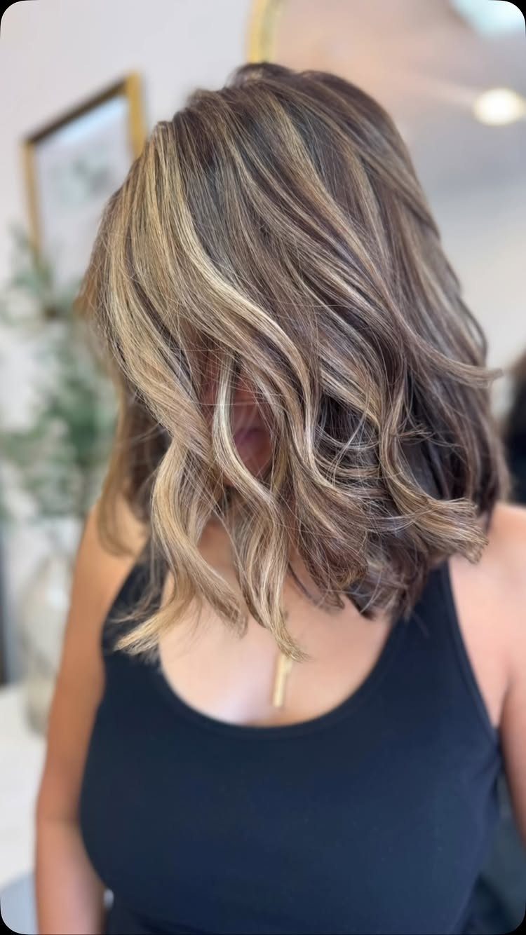 Short layered blonde hair with darker lowlights and loose waves