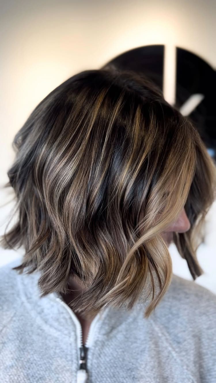 Short brunette waves with caramel balayage highlights and lighter strands