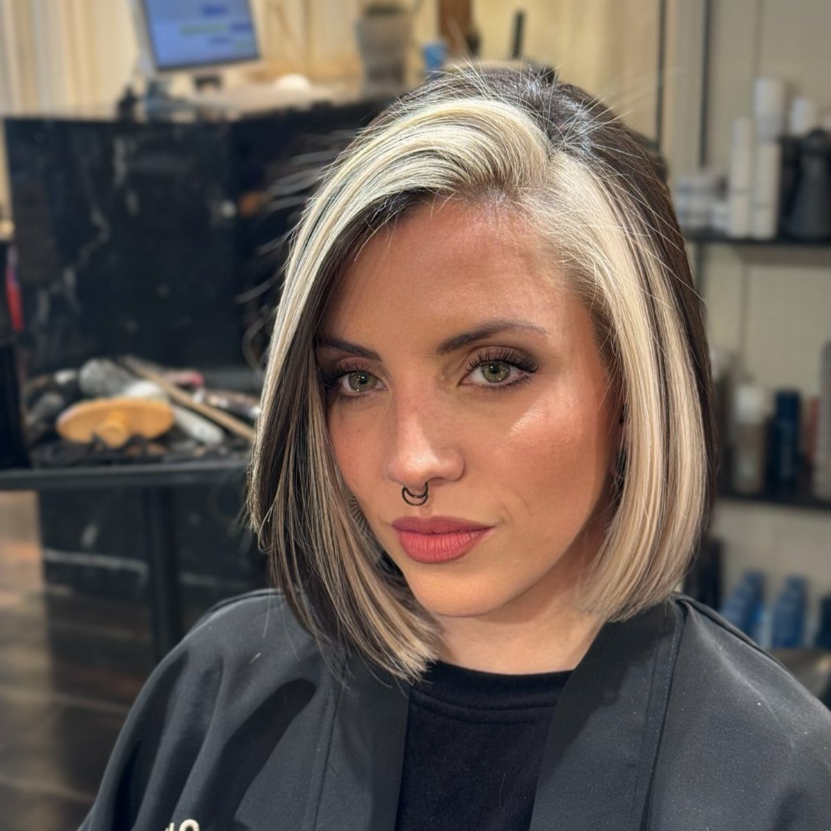 Woman with a short blonde bob, dark roots, and lighter ends in a salon