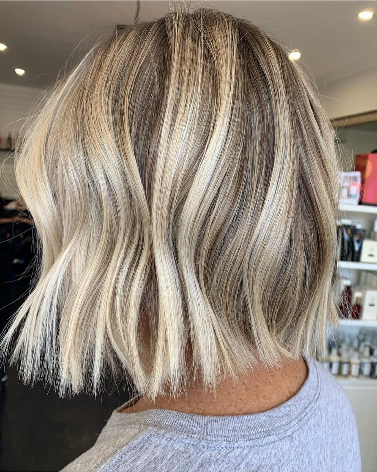 Shoulder-length wavy lob with blended blonde balayage and darker roots