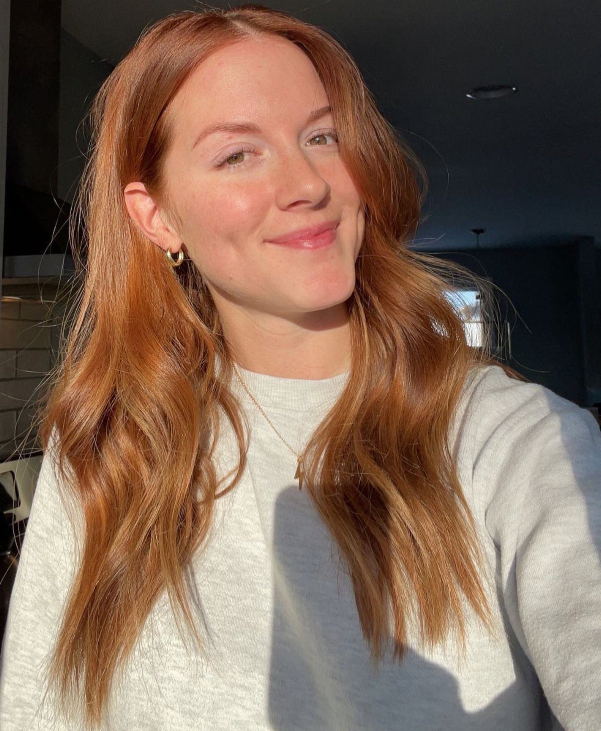 Woman with long, warm copper strawberry-blonde hair in sunlight