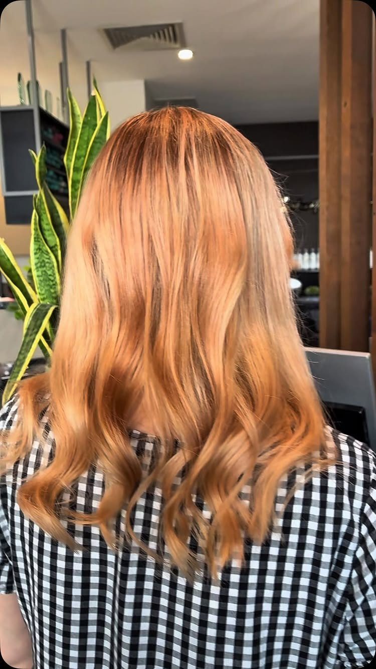 Long wavy strawberry blonde hair with creamy blonde tones in a salon