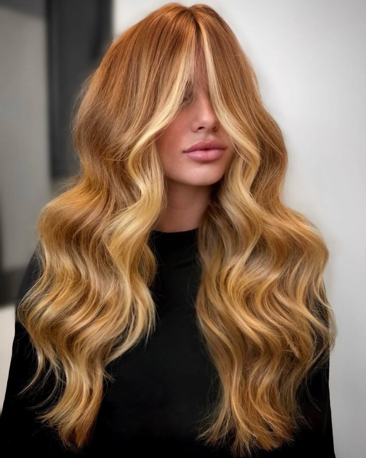 Woman with long copper-blonde waves and golden face-framing highlights