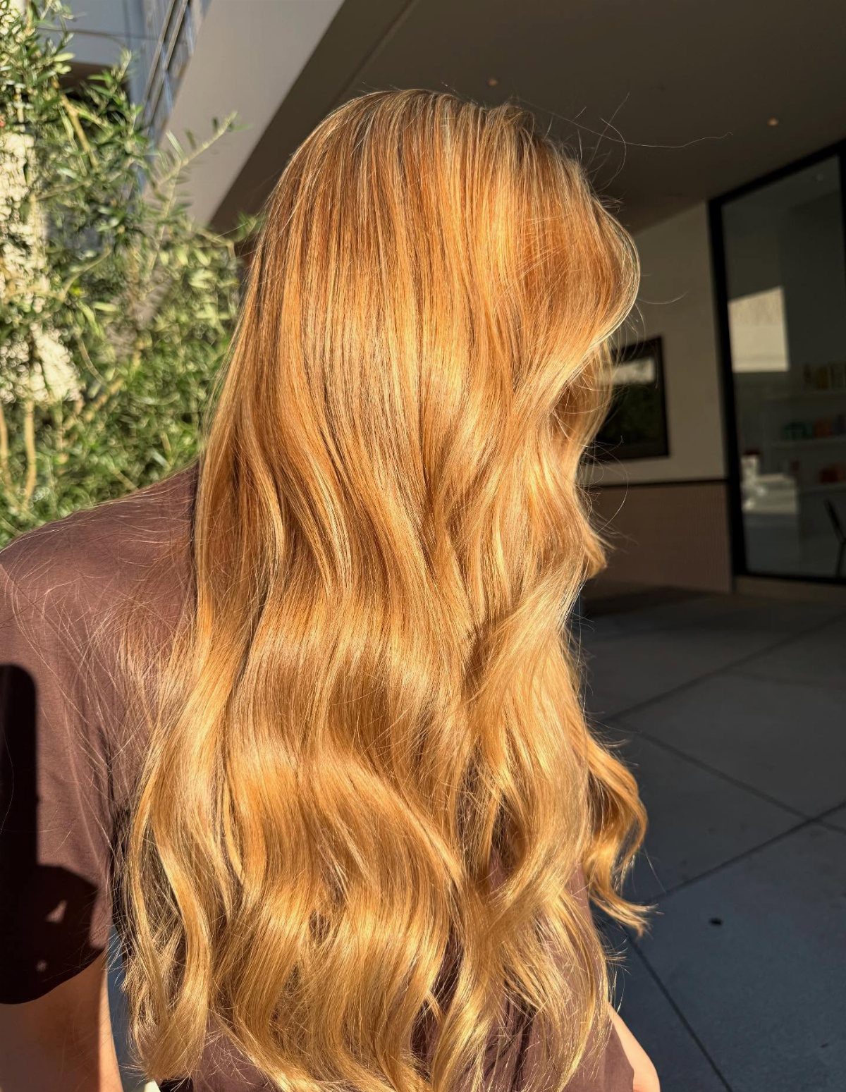 Long wavy strawberry-blonde hair woven with honey-gold highlights in sunlight