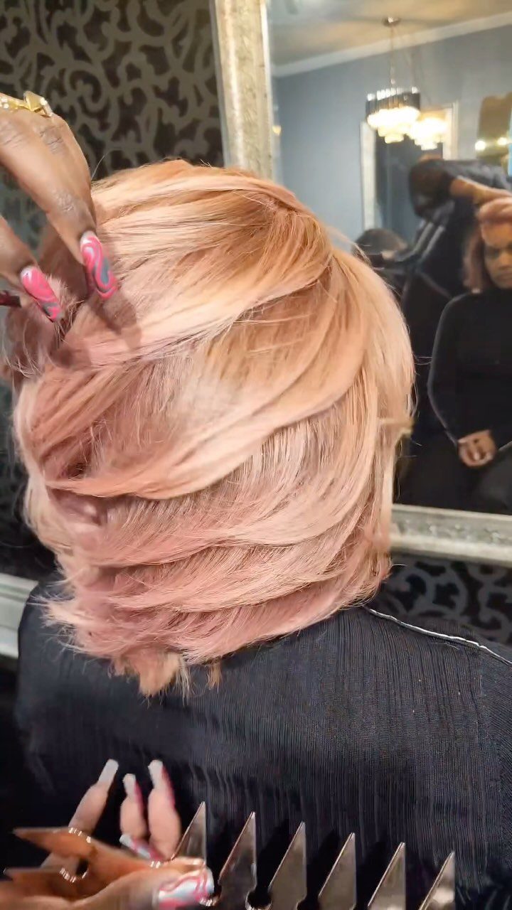 Pale pink-blonde hair styled in soft layered sections at a salon