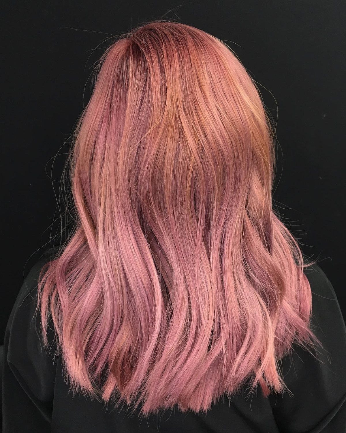 Long wavy power-pink hair with warm blonde and strawberry-toned highlights