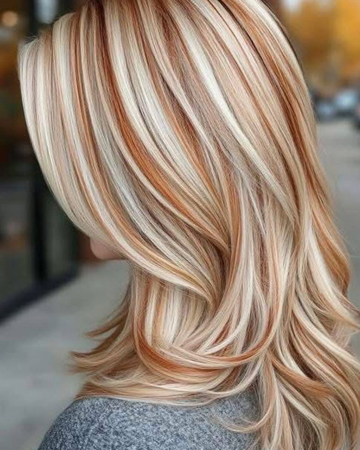 Layered blonde hair with warm strawberry and copper highlights