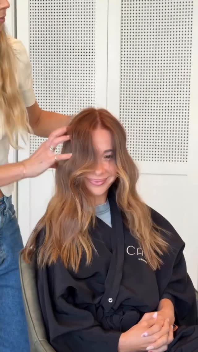 Seated woman showing wavy strawberry bronde hair in a salon